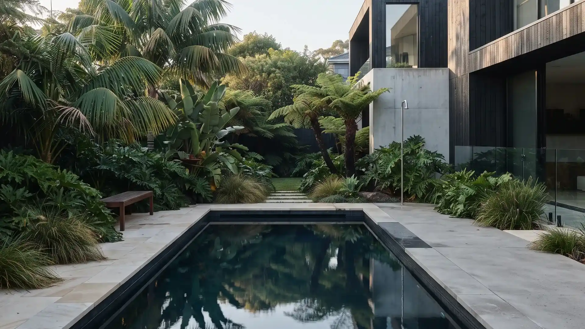 Contemporary backyard pool with pale stone coping and subtropical planting
